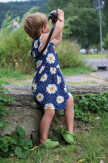 Full length of girl playing with camera on field