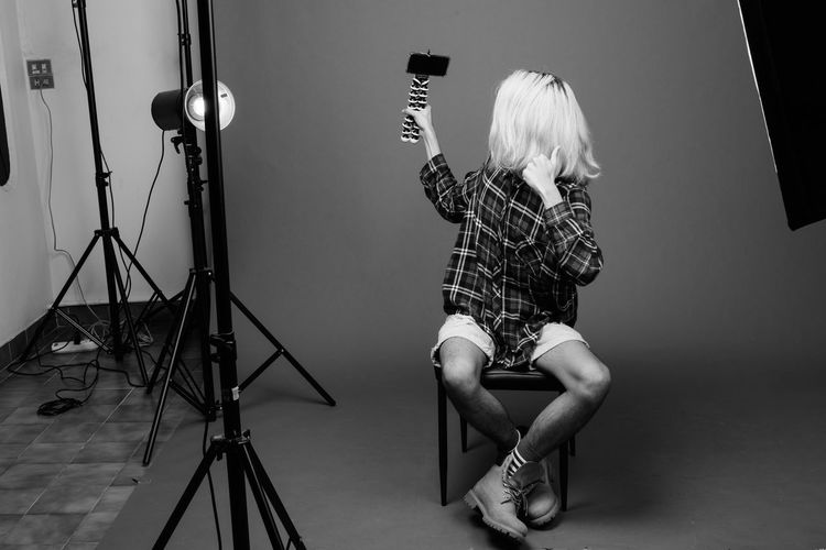 Midsection of woman photographing against gray background