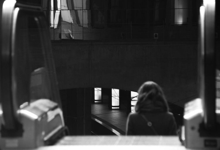 Rear view of woman moving down on escalator at railway station