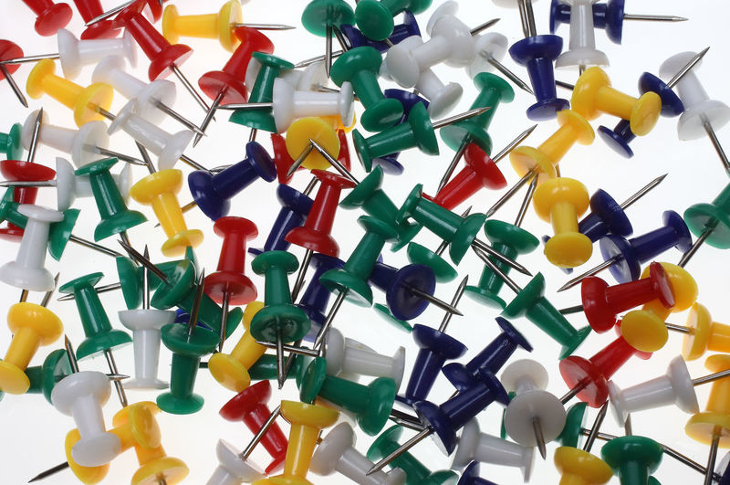 High angle view of multi colored thumbtacks on white background