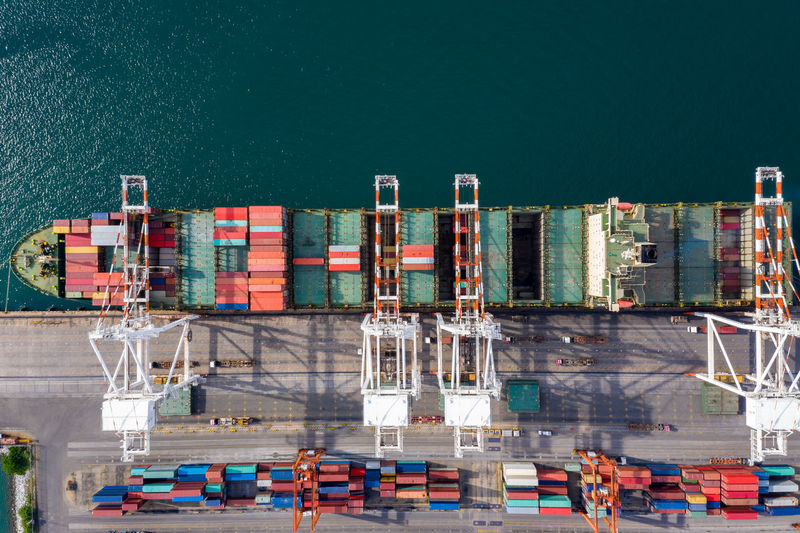 High angle view of commercial dock and shipping containers loading against sea