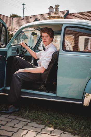 Portrait of young man sitting in vintage car