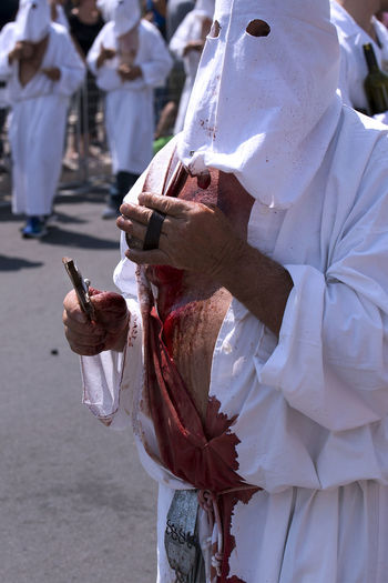 Man with injured body holding equipment during religious event