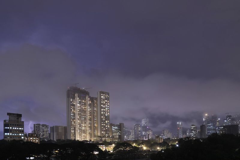 Illuminated buildings in city against sky at night