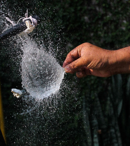 Cropped hand exploding water bomb