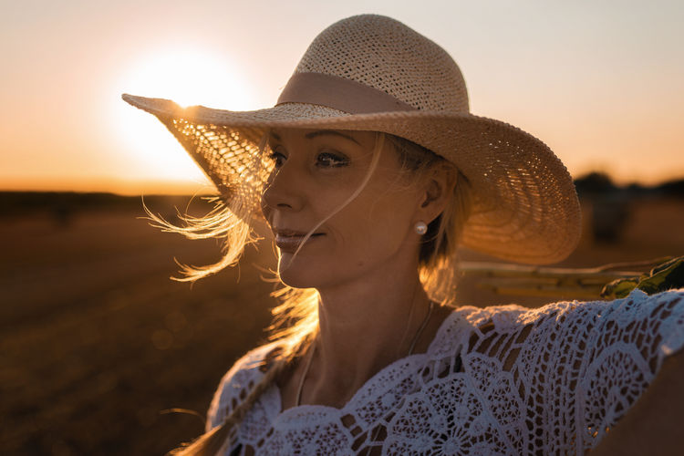 Portrait of woman wearing straw hat against sky during sunset