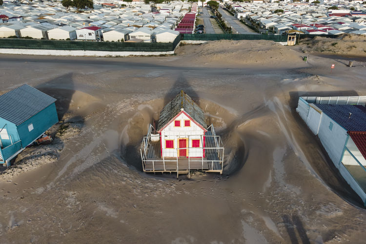 Portugal, setubal district, costa da caparica, drone view of small wooden houses along sandy beach