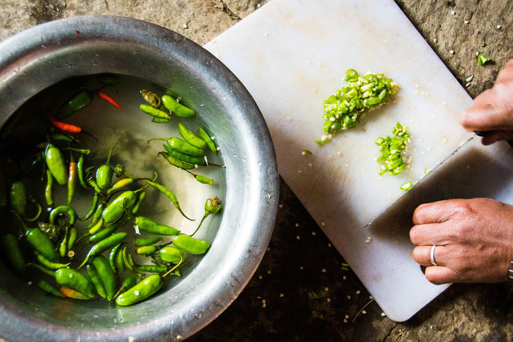 Close-up of hands cutting green chilies