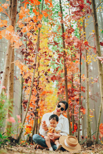 Portrait of mother with son sitting in forest during autumn