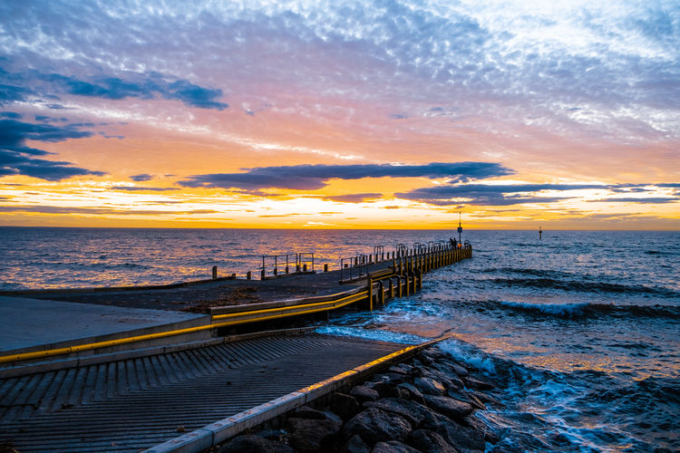 Beautiful glowing sunset over ocean and small boat jetty in melbourne, australia