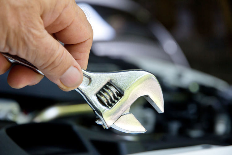 Close-up of man holding wrench against car