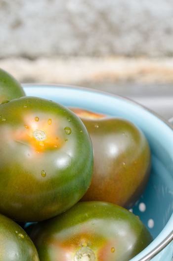 Close-up of unripe tomatoes in colander on table