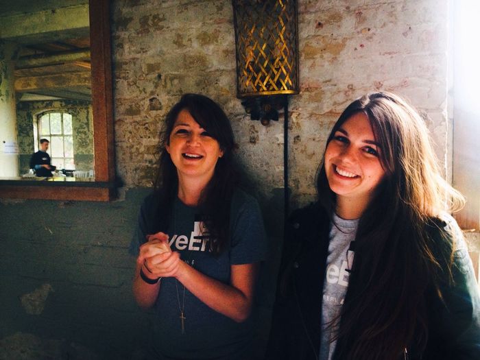 Portrait of friends smiling while standing against wall