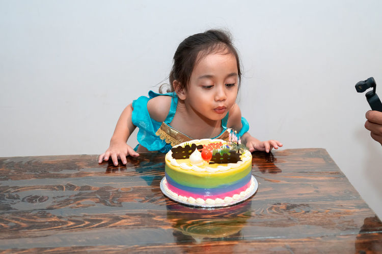 Little girl is blowing candles on her birthday cake. celebrating at home during quarantine.