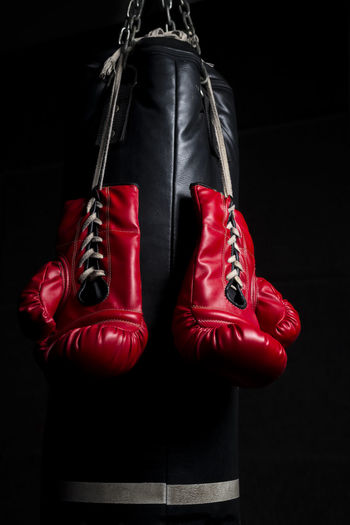 Close-up of boxing gloves hanging against black background