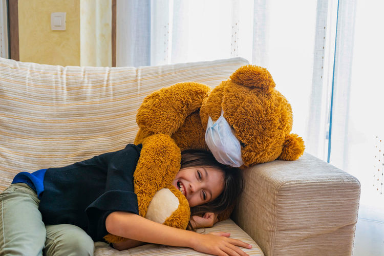 Smiling girl playing with teddy bear at home