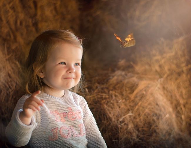 Cute girl smiling while looking at butterfly