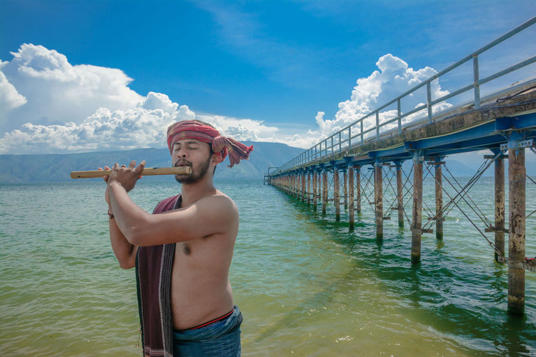 Playing traditional flute in shores of lake toba