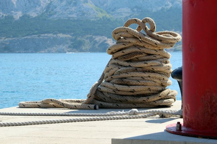 Close-up of rope tied to stack on shore