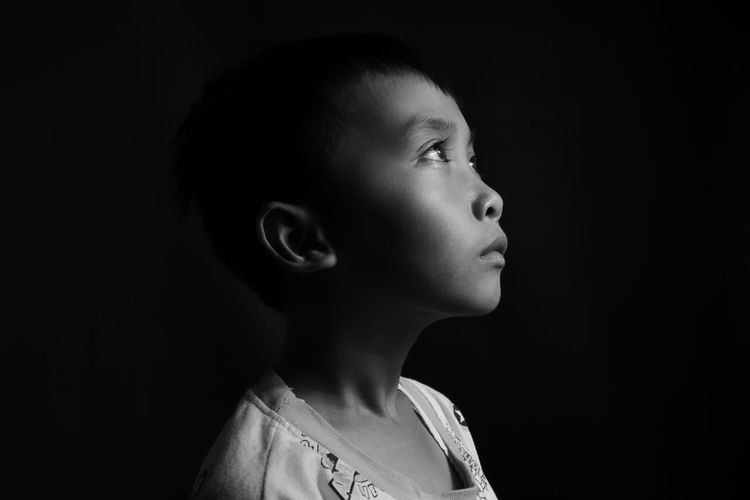Portrait of boy looking away against black background