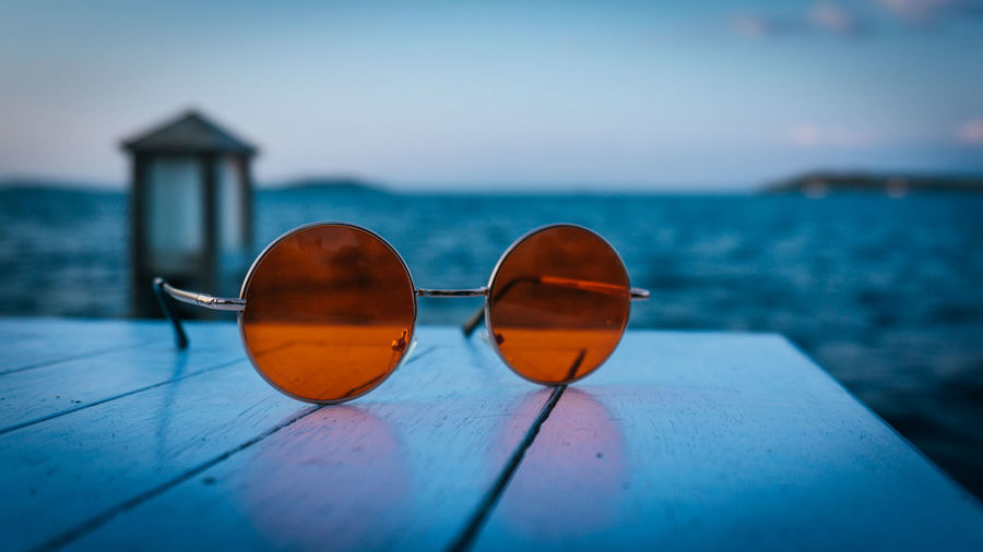 Close-up of sunglasses against blue sea