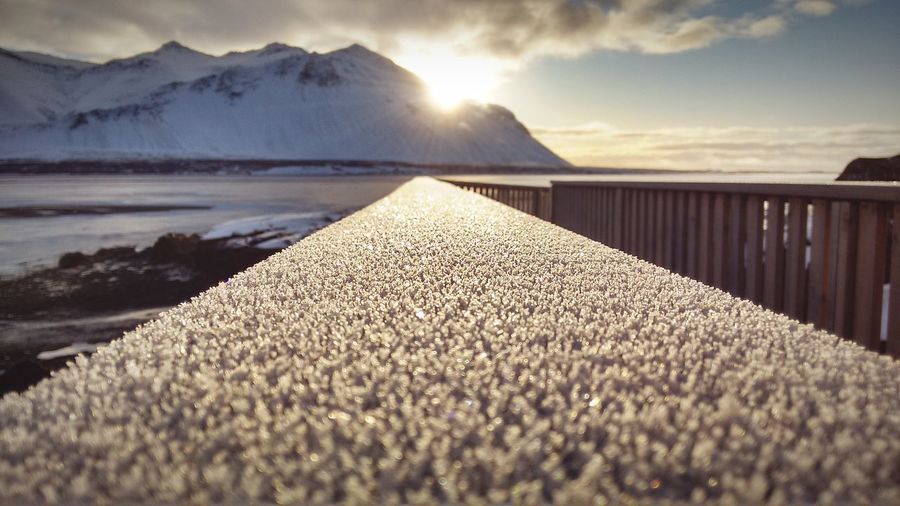 Surface level shot of snow against mountains during sunset