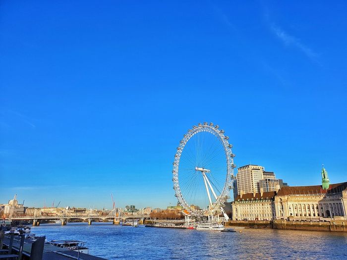 Ferris wheel in city against blue sky