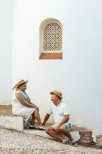 Happy senior tourist couple sitting on steps in a village, el roc de sant gaieta, spain