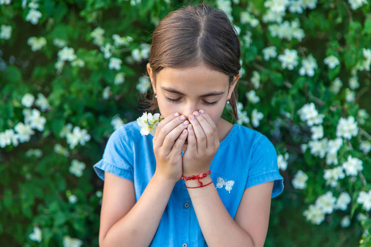 Girl sneezing while smelling flower