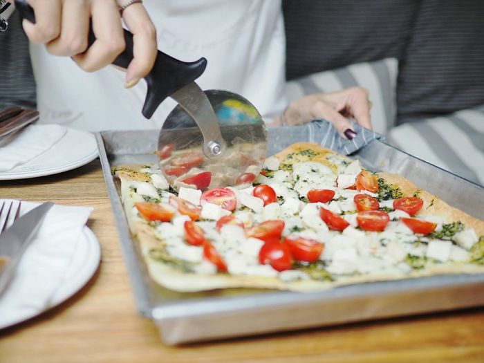 Close-up of hand cutting pizza with pizza cutter