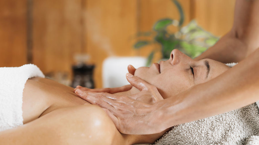Woman enjoying professional ayurveda neck and shoulders massage with ethereal oil