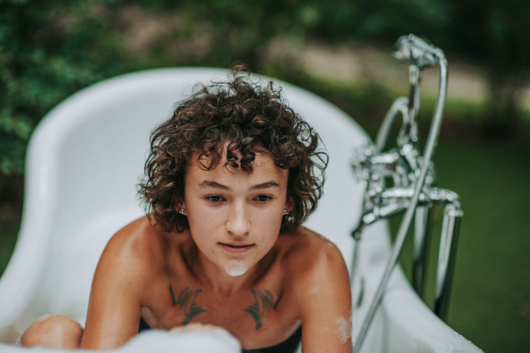 Young woman sitting in bathtub outdoors