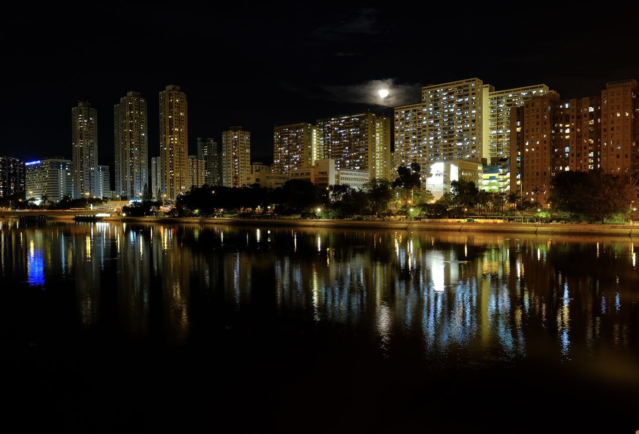 REFLECTION OF ILLUMINATED BUILDINGS ON WATER AT NIGHT