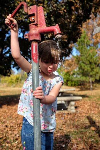 Cute girl using water pump on sunny day