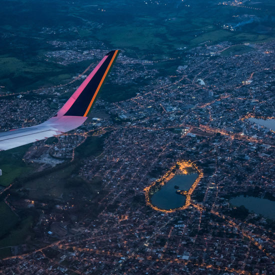 Cropped image of airplane wing flying over cityscape at dusk
