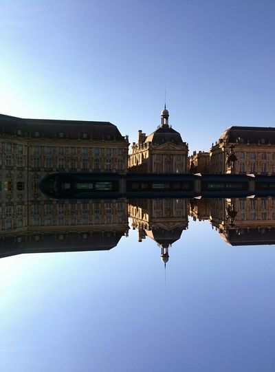 Place de la bourse reflecting in miroir d eau against clear sky
