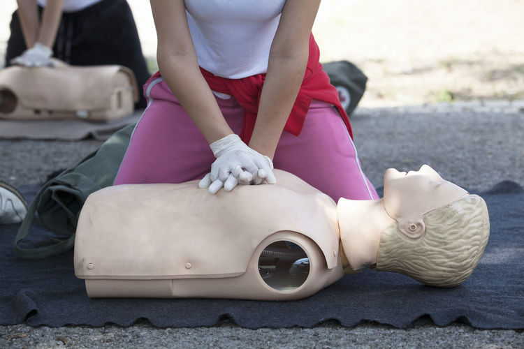Midsection of paramedic performing cpr on mannequin