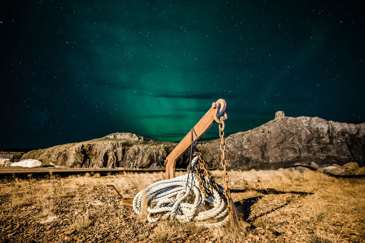 Man on rock by lake against sky at night
