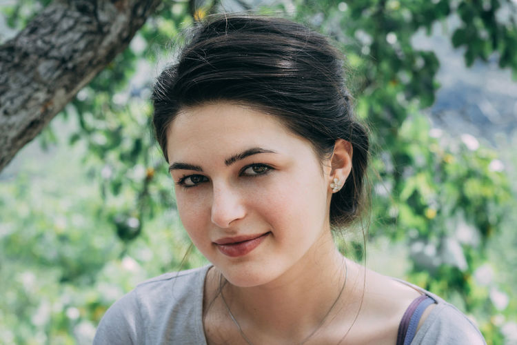 Portrait of young woman against tree