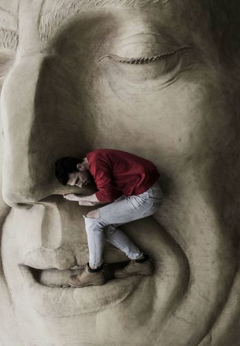 Side view of woman standing on human sculpture
