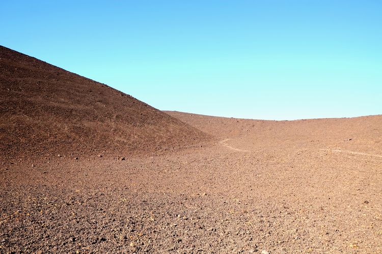 Scenic view of arid landscape against clear blue sky