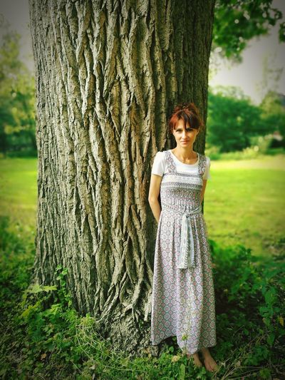 Portrait of teenage girl standing on tree trunk
