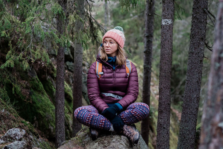 Woman sitting on a rock thinking whilst hiking in the forest in sweden
