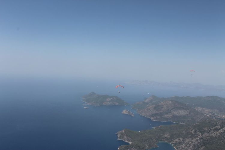 Aerial view of sea and mountains against clear blue sky