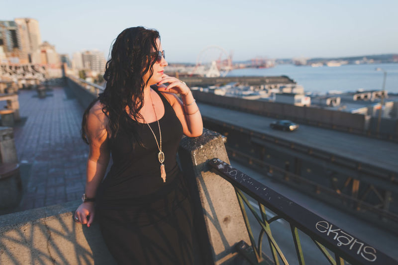 Woman standing by railing against sky