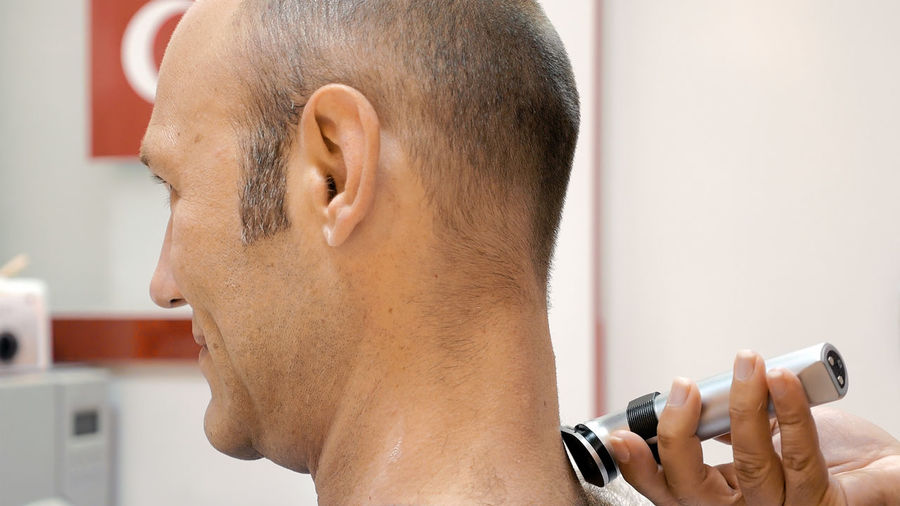 Barber trimming neck hair of mature man in salon