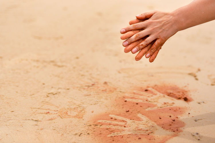 Cropped hands over sand at beach