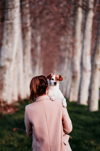 Rear view of woman with dog walking in forest