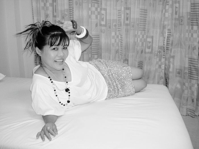 Portrait of smiling woman relaxing on bed at home