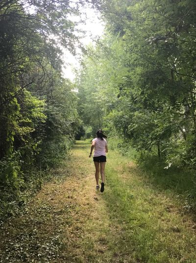 Full length rear view of woman running in forest